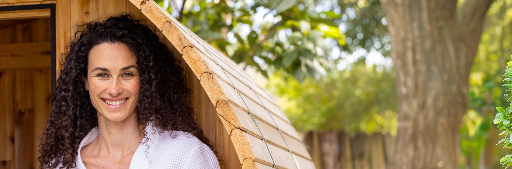 Woman holding rachel perry natural skincare products outside a wooden sauna