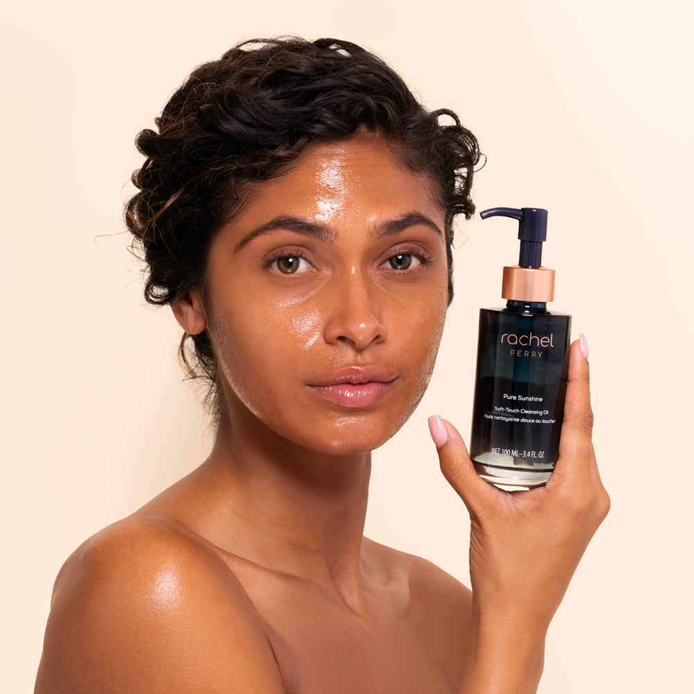 Woman holding a bottle of rachel perry natural skincare product against a beige background