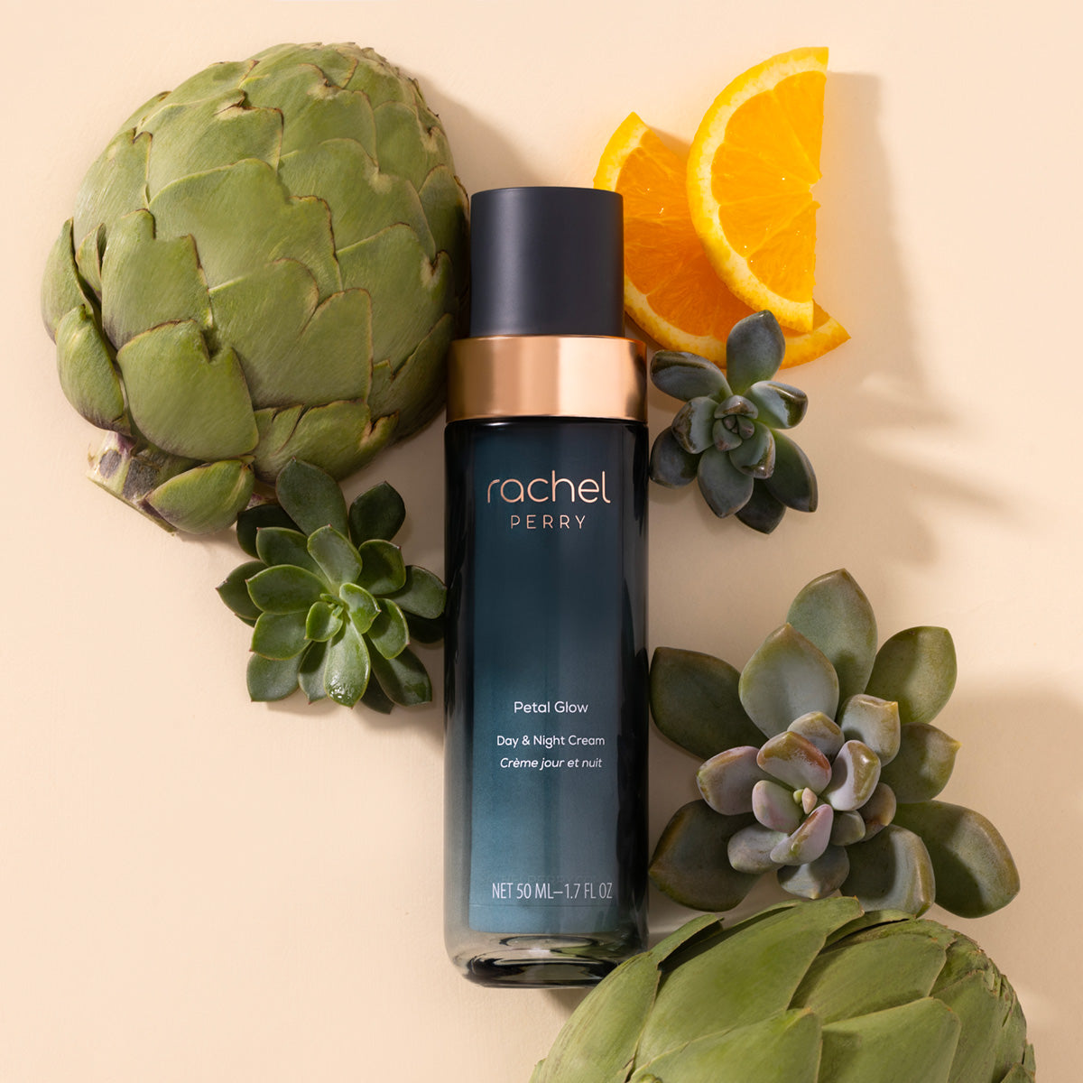natural clean moisturizer bottle labeled rachel perry petal glow day night cream surrounded by artichokes, oranges, and succulents on a beige background