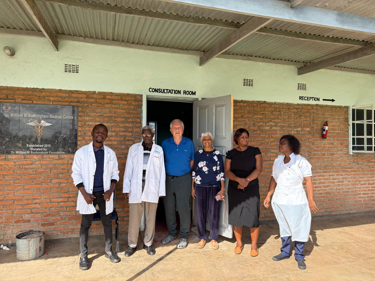 6 people standing in front of dr william m buckingham center in Malawi africa for 11 lights foundation