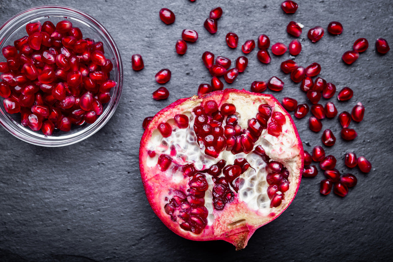 Pomegranate and its seeds on a dark surface natural clean ingredient skincare