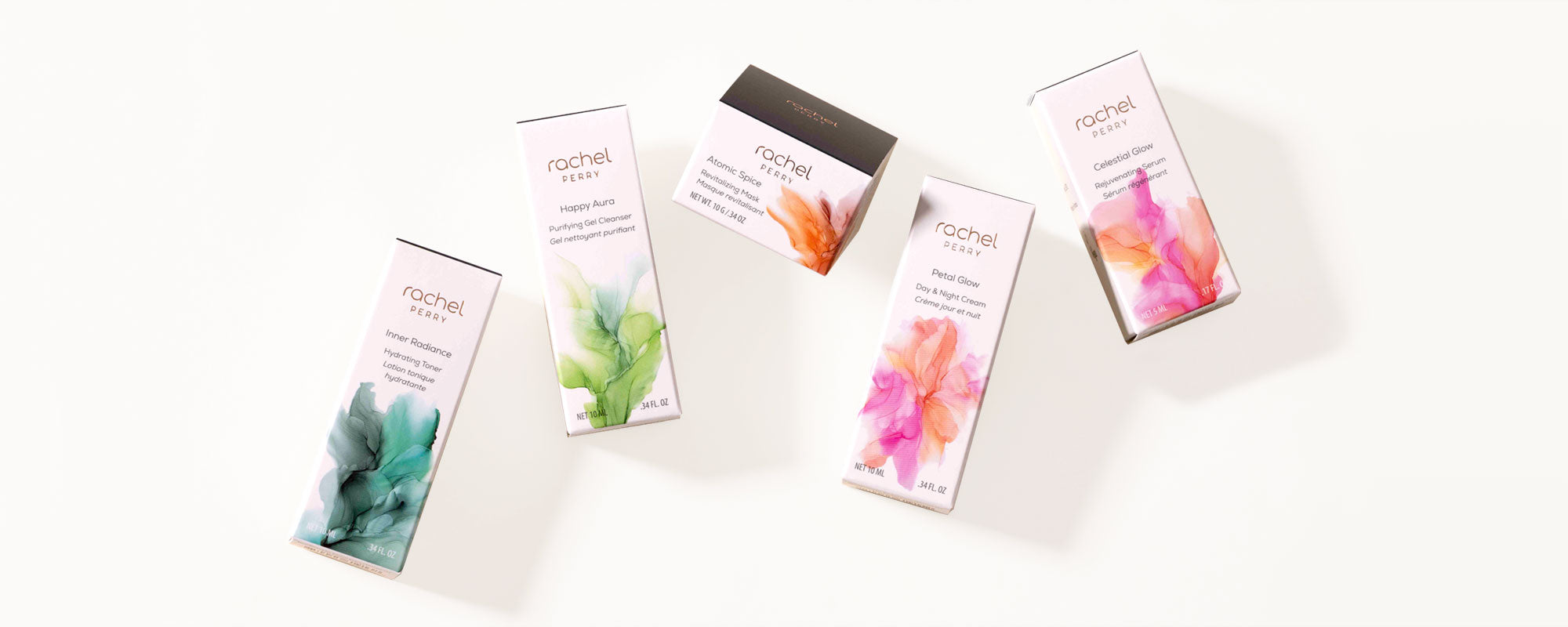 Five small boxes of rachel perry natural skincare travel sizes with colorful floral designs on a white surface